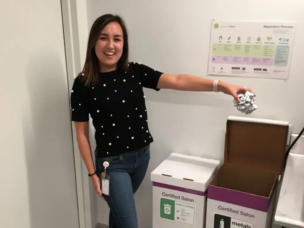 A Henkel employee demonstrates how to properly recycle salon waste using the various bins provided by Green Circle Salons.