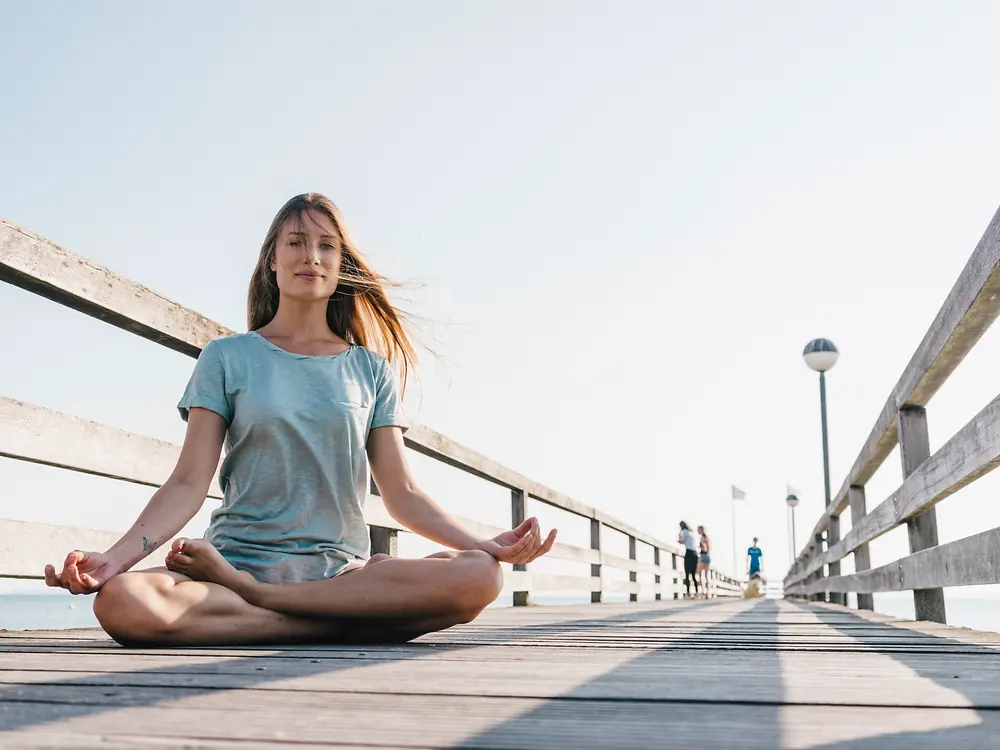 Woman meditating on the pier