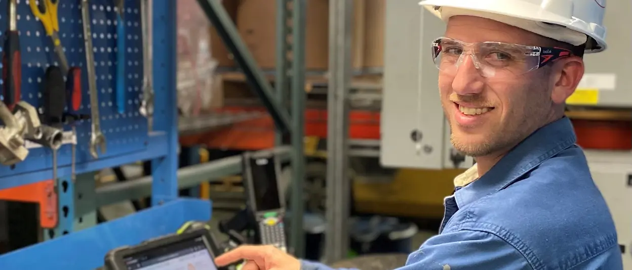 Employee wearing hard hat and holding tablet