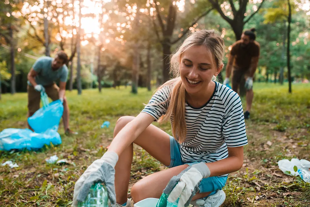 A woman and two men collect plastic waste from the nature