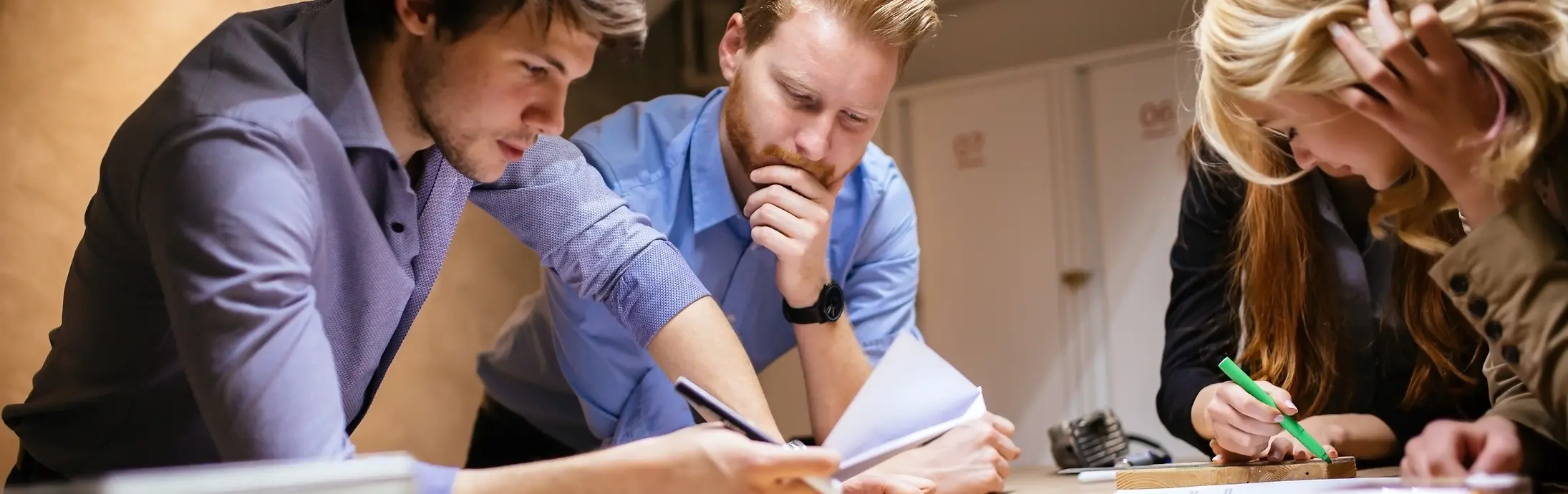 A group of 4 colleagues leaning on a table and checking some papers