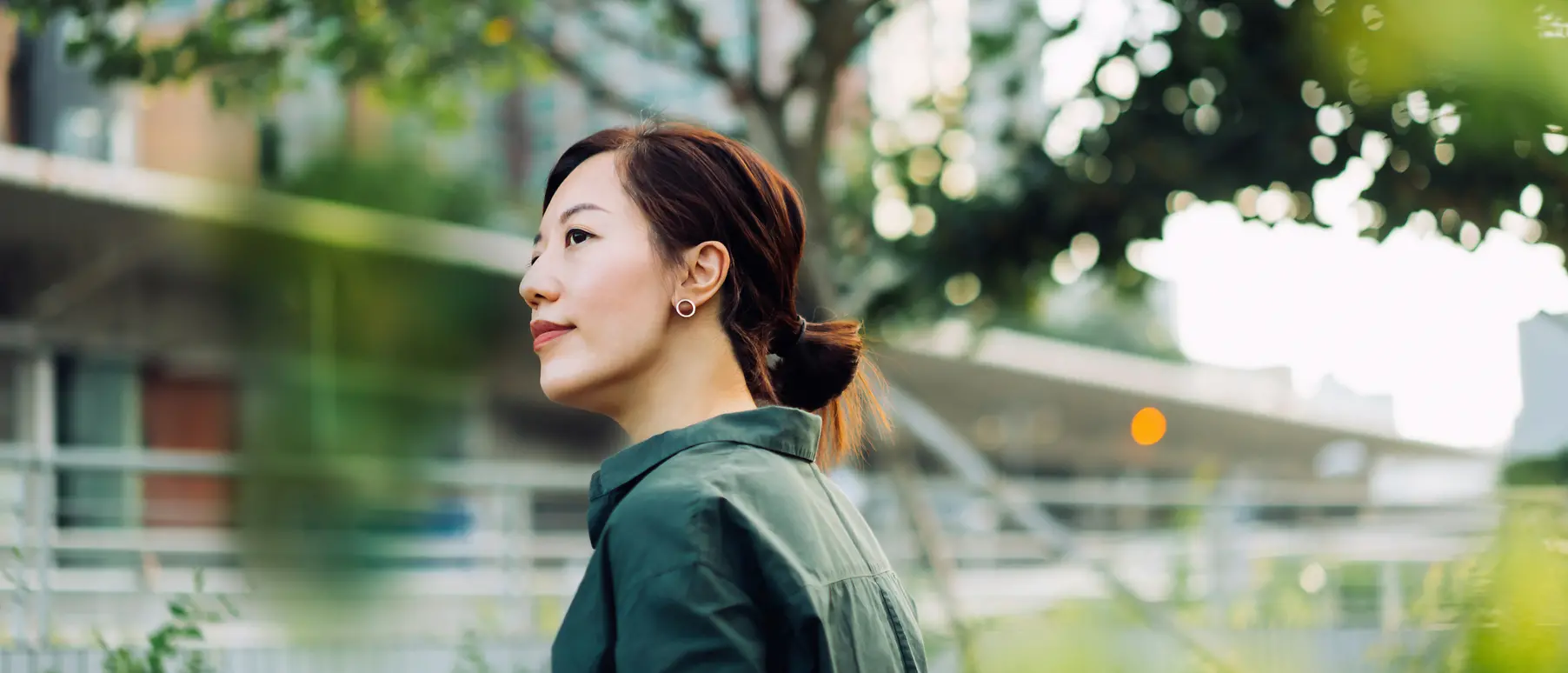 woman slightly smiling, trees in the background