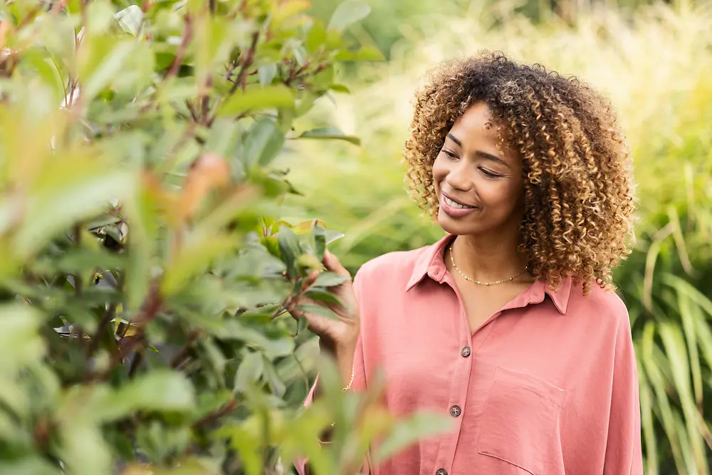 woman smiling, looking at a tree branch