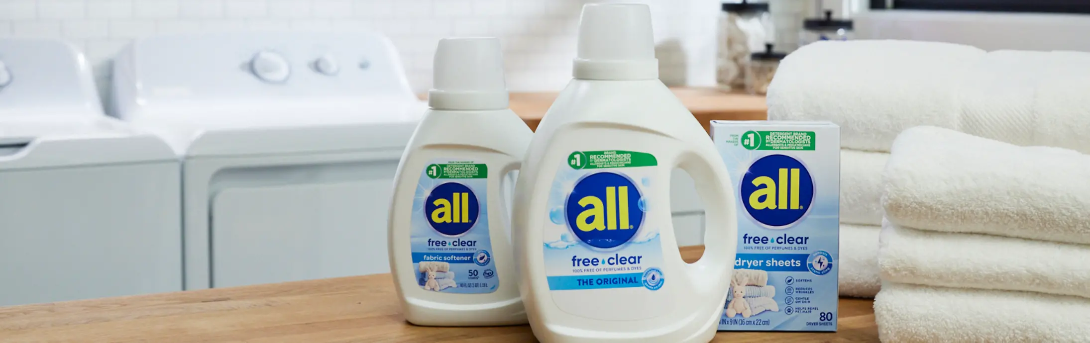 Woman holds child in a laundry room, using a bottle of all free clear detergent