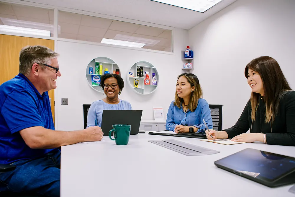 A group of four employees sitting around a table discussing a topic.