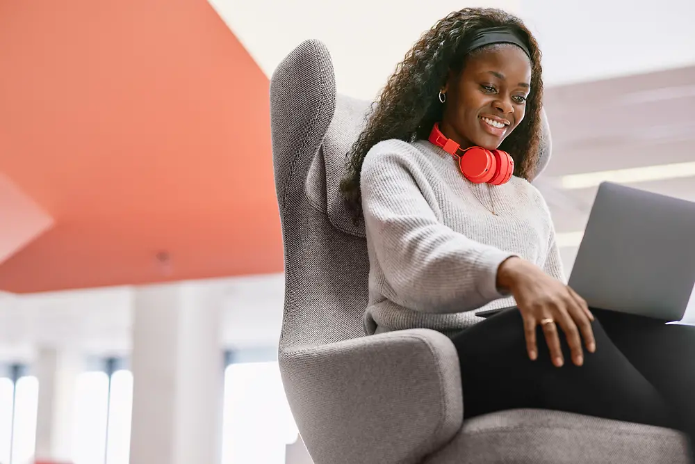 A young woman sits in front of her computer smiling and studying.