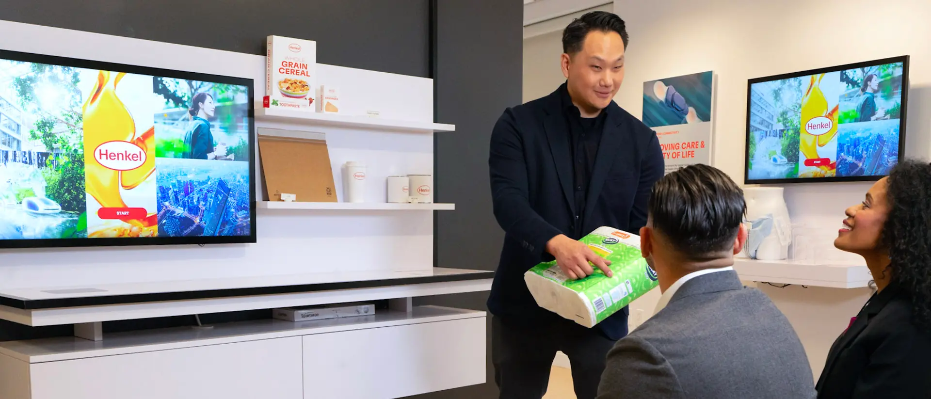 A customer experience tour guide presents application examples from Henkel Adhesive Technologies to two customers at the Technology Center Bridgewater.