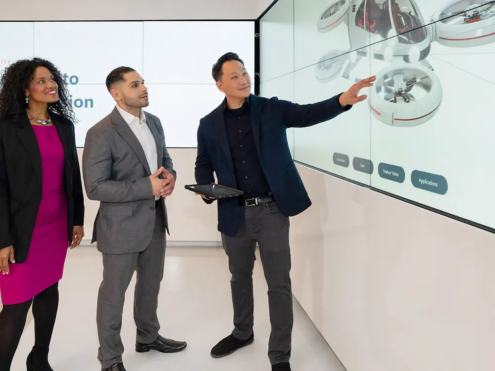 A customer experience tour guide showing two customers interactive content in the Infinity Room of the Technology Center Bridgewater.