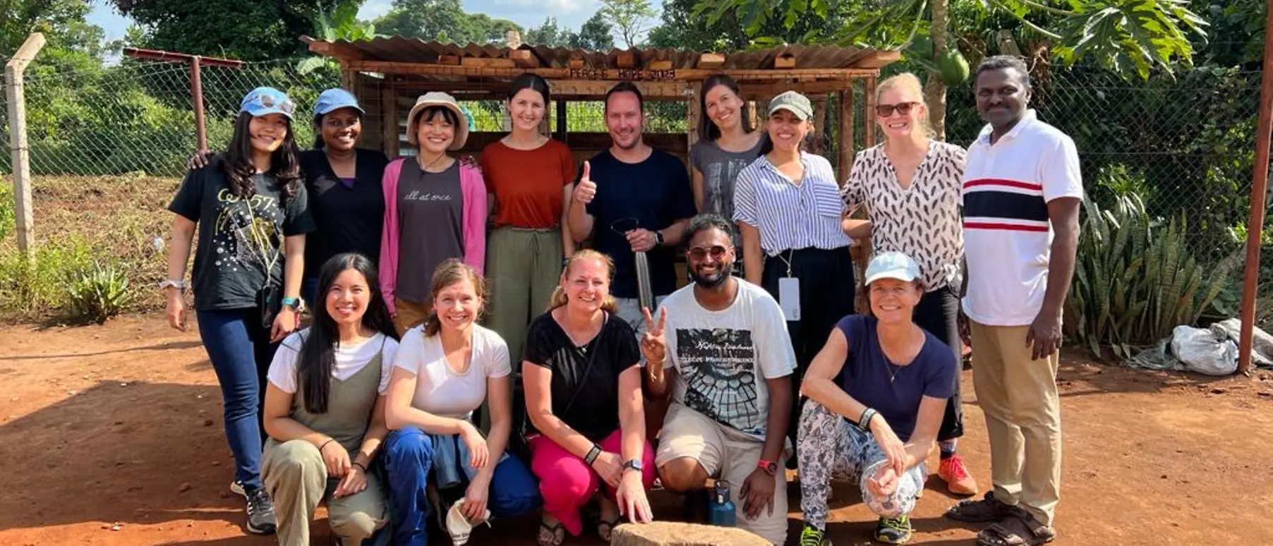 The participants of the team trip organized by Peace's Hope stand in front of the chicken coop they built together.