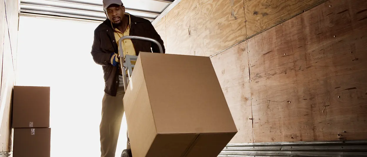 A man is loading boxes into a truck. 