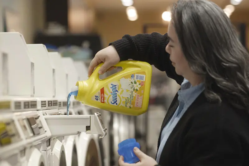 woman pouring Sunlight laundry detergent into washing machine