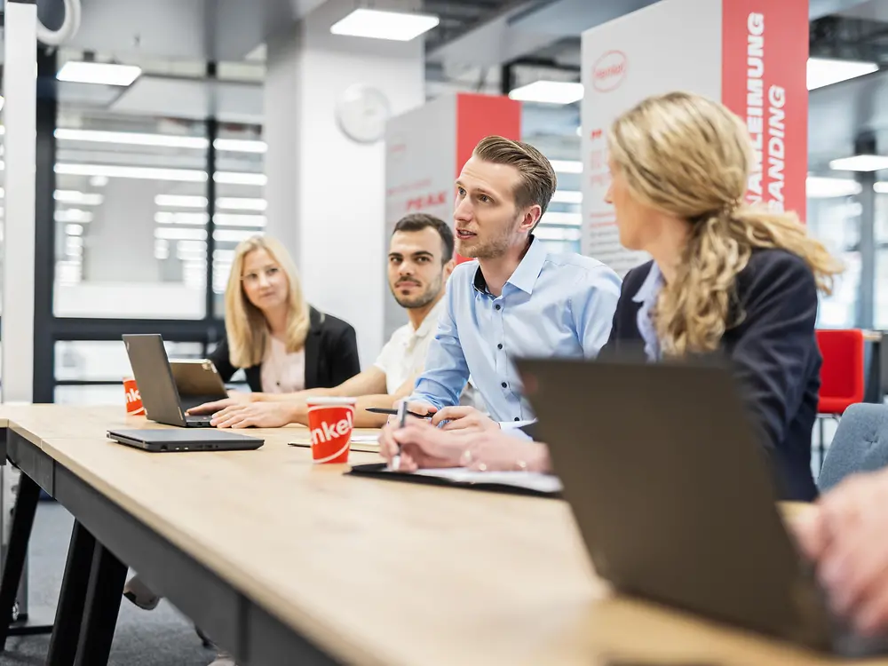 A group of people work while sitting at a table.