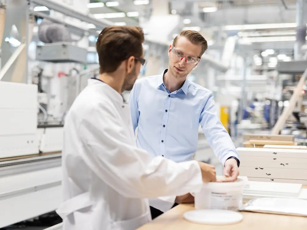 Two people talk while on a factory floor.