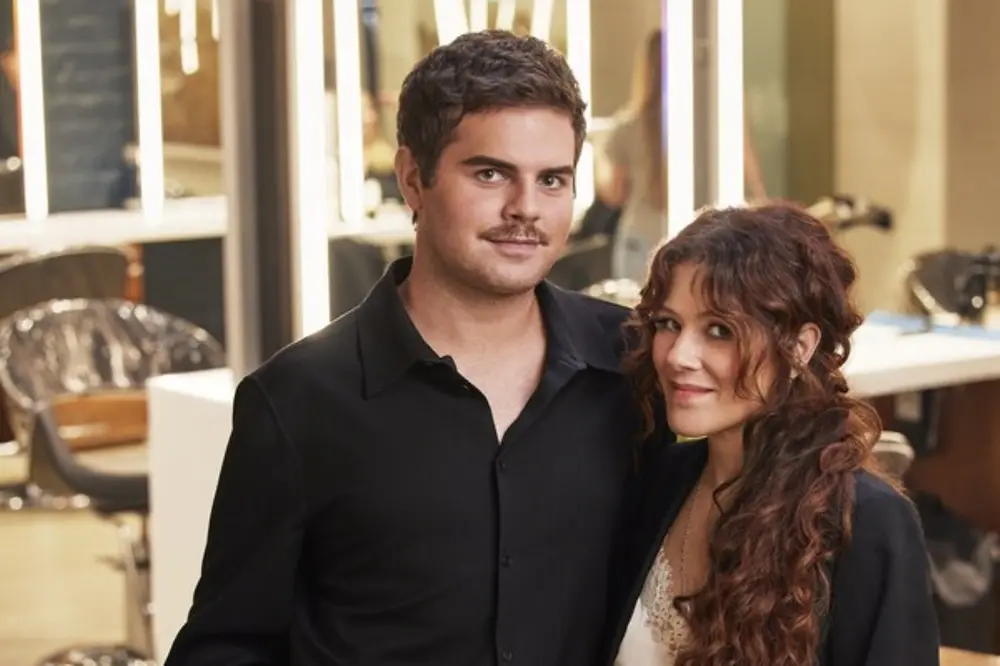 A man and a woman dressed in black in front of a mirror