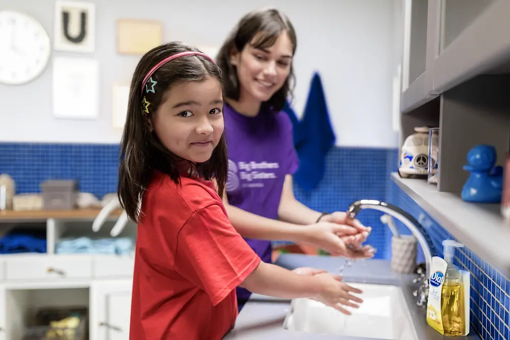 A girl with her 'Big Sister' in a bathroom, washing their hands with Dial soap